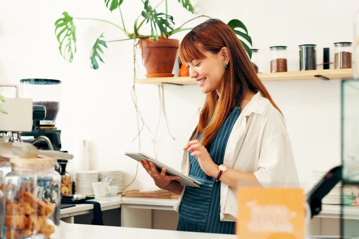タブレットを操作しながら笑顔のカフェスタッフ