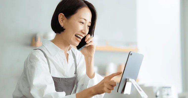 電話をしながらタブレットを操作するスタッフ
