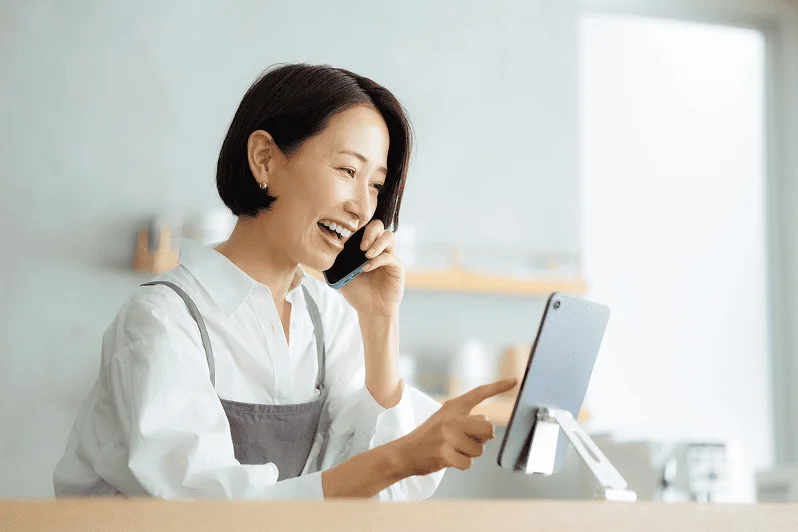 電話をしながらタブレットを操作するスタッフ