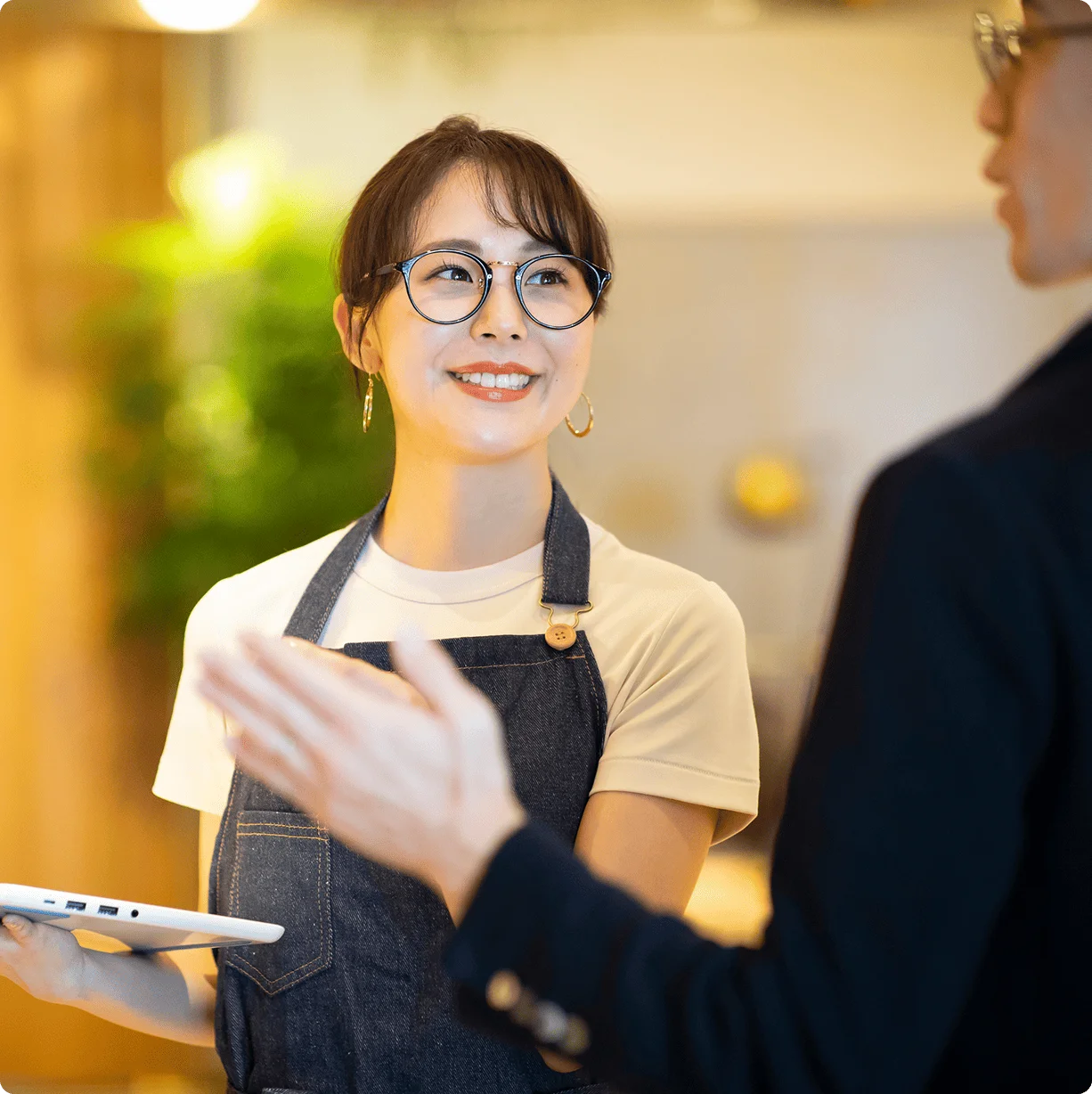 タブレットを持ちスタッフと話す女性店員